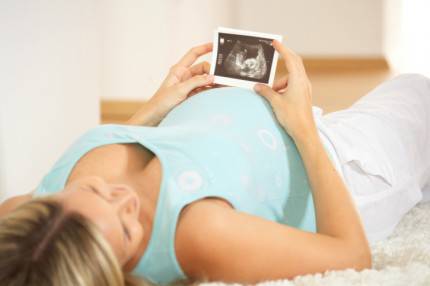 Donna incinta con in mano un'immagine ecografica del feto