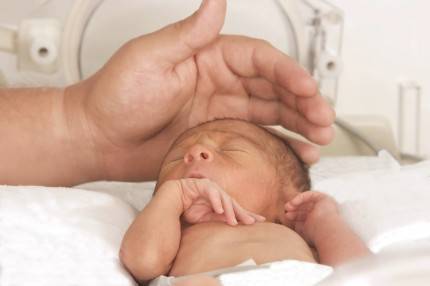 Neonato prematuro in incubatrice che riceve una carezza