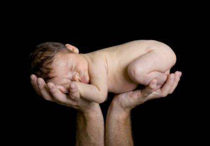 Bambino appena nato sollevato con due mani