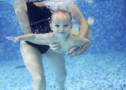 Piccolo bambino sorride dentro l'acqua di una piscina