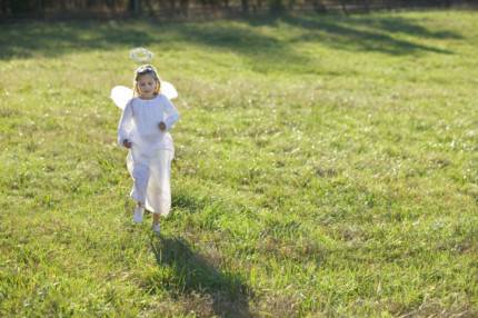 Bambina che corre vestita da angelo