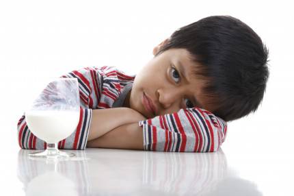 Bambino di fronte a bicchiere di latte
