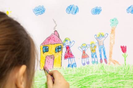 una bambina disegna la sua famiglia