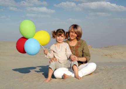 Madre e figlia in spiaggia con palloncini colorati