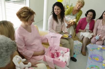 Donna incinta che apre un regalo durante un baby shower