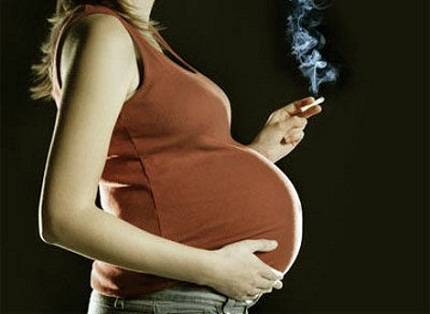Donna incinta con sigaretta in mano 