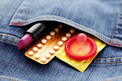 Una confezione di pillola anticoncezionale e un preservativo escono da una tasca di un paio di jeans