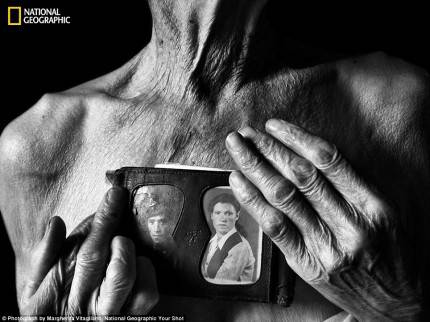 torace di uomo nudo anziano che tiene in mano foto di uomo e donna