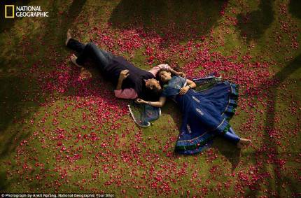 uomo e donna distesi su un prato attorniati di petali di rose