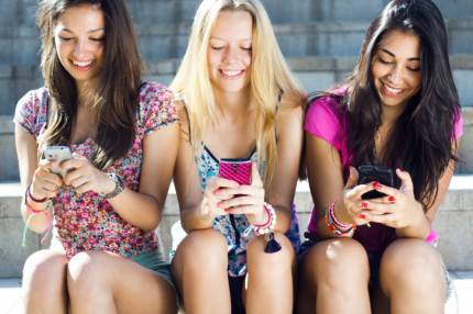 Tre ragazze adolescenti chattano con il loro smartphone