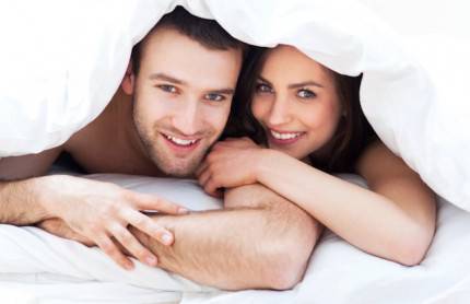 Una donna e un uomo sono sorridenti sotto le coperte