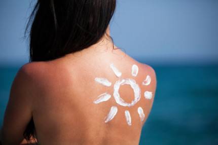 schiena di donna al sole con crema protezione solare sulla spalla