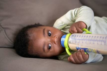 baby feeding himself a bottle of milk