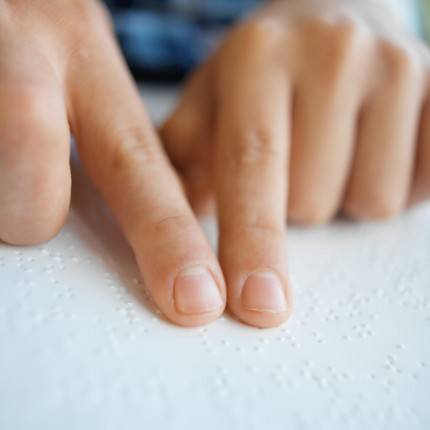 close up view of the fingers of a person reading by Braille