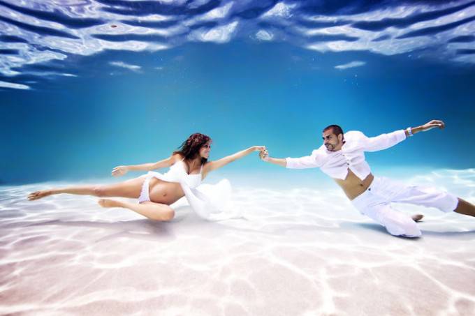 donna e uomo sott acqua vestiti bianco