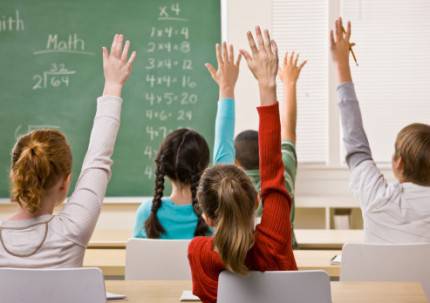 bambini a scuola con le mani alzate