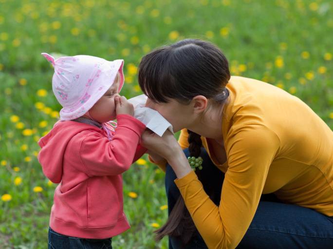 Bambina starnutisce vicina a sua mamma su un prato