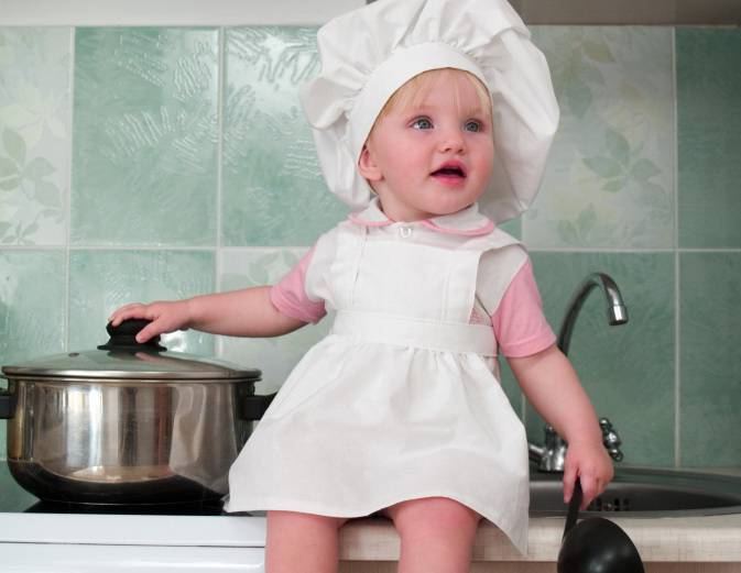 Bambina con cappello da chef vicino a pentola