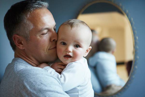 papà in età avanzata bacia figlio piccolo tenedolo in braccio